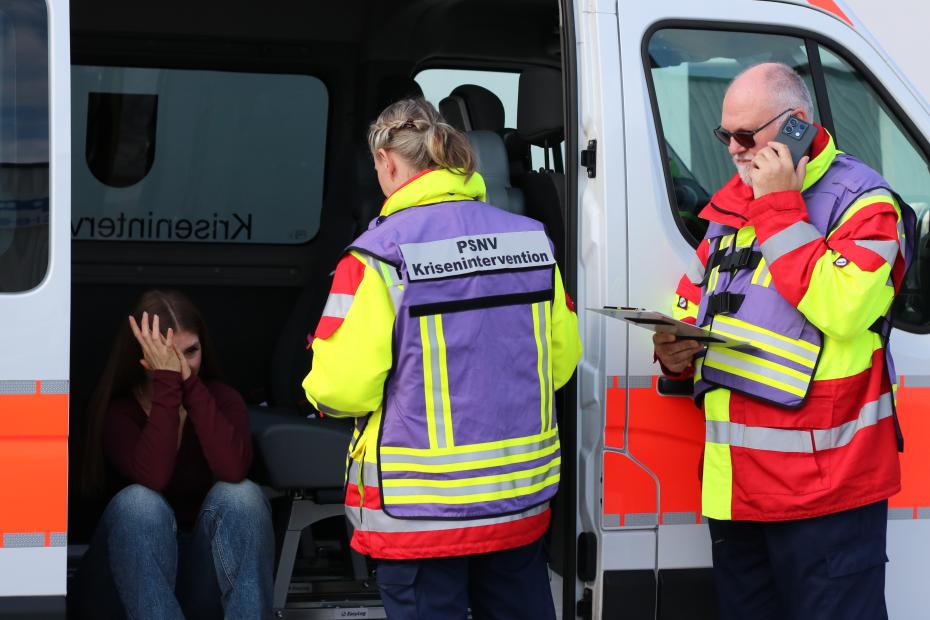 Team der PSNV vor dem Einsatzwagen kümmert sich um Patientin